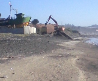 Máquina retroexcavadora se lleva camionadas de arena desde Playa Negra en Coronel