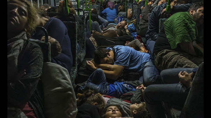 Refugiados duermen en un bus tras salir de Budapest a Viena | Pulitzer
