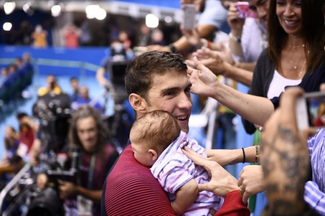 USA's Michael Phelps (L) holds his son Boomer after he won the Men's 200m Butterfly Final during the swimming event at the Rio 2016 Olympic Games at the Olympic Aquatics Stadium in Rio de Janeiro on August 9, 2016.   / AFP PHOTO / Martin BUREAU