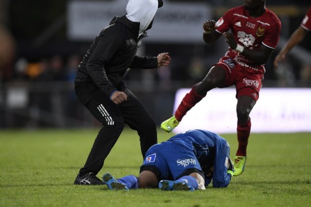 Ostersund's goalkeeper Aly Keita (C) remains on the ground after a masked soccer spectator (L) attacked him during a football match between Jonkoping Sodra and Ostersund in Jonkoping on August 15, 2016. / AFP PHOTO / TT NEWS AGENCY / Mikael Fritzon / Sweden OUT