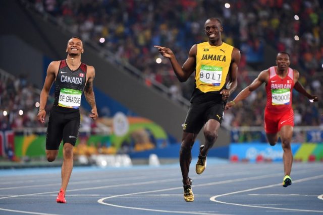 Jamaica's Usain Bolt (C) jokes with Canada's Andre De Grasse (L) after they crossed the finish line in the Men's 200m Semifinal during the athletics event at the Rio 2016 Olympic Games at the Olympic Stadium in Rio de Janeiro on August 17, 2016.   / AFP PHOTO / OLIVIER MORIN