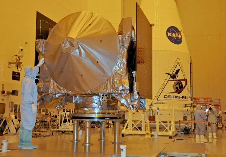 The OSIRIS-REx spacecraft sits on its workstand August 20, 2016 while an engineer checks the protective covering in a servicing building at Kennedy Space Center, Florida.    The OSIRIS-REx is scheduled to launch aboard an Atlas 5 rocket September 8, 2016 on its mission to the asteroid Bennu.         / AFP PHOTO / Bruce Weaver