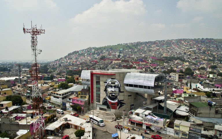 View of a cable car station decorated with a mural of Icelandic artist Guido Van Helten  at a poor neighborhood in Ecatepec, Mexico on August 25, 2016.  Dozens of murals were painted on buildings in a poor neighborhood in Ecatepec, on the route of a new cable car that will run this year. / AFP PHOTO / MARIO VAZQUEZ / TO GO WITH AFP STORY BY JENNIFER GONZALEZ