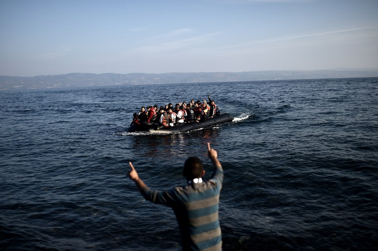 Refugees and migrants aboard a dinghy reach the shores of the Greek island of Lesbos, after crossing the Aegean sea from Turkey on October 4, 2015. For the thousands of refugees and migrants landing on its beaches every day, Greece