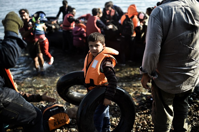 A young boy holding rubber ring buoys is pictured after reaching with other refugees and migrants aboard dinghies the Greek island of Lesbos, crossing the Aegean sea from Turkey on October 4, 2015. For the thousands of refugees and migrants landing on its beaches every day, Greece