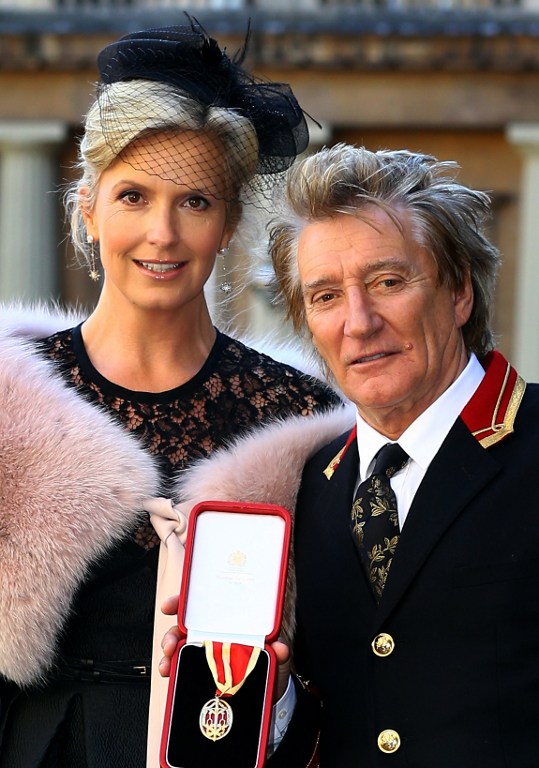 Scottish singer Rod Stewart stands with his wife Penny Lancaster, as he poses for a photograph with his insignia of Knighthood medal, after being presented with it during an investiture ceremony at Buckingham Palace in London on October 11, 2016