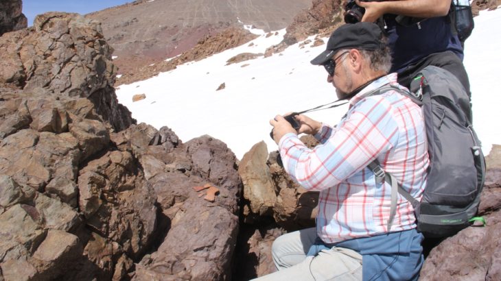 El Dr. Rubén Stehberg fotografiando la roca ceremonial o "huaca" del sitio.