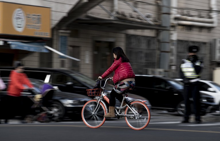This picture taken on January 31, 2017 shows a girl riding a Mobike bicycle on the street in Shanghai. 