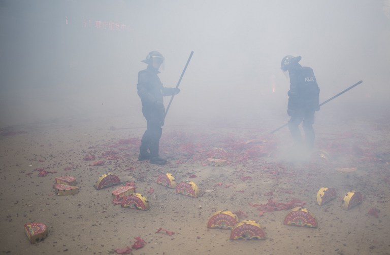 Johannes Eisele | Agencia AFP This picture taken on February 9, 2017 shows police monitoring the area where firecrackers are being set off during a festival, along a street in the village of Tufang in eastern China