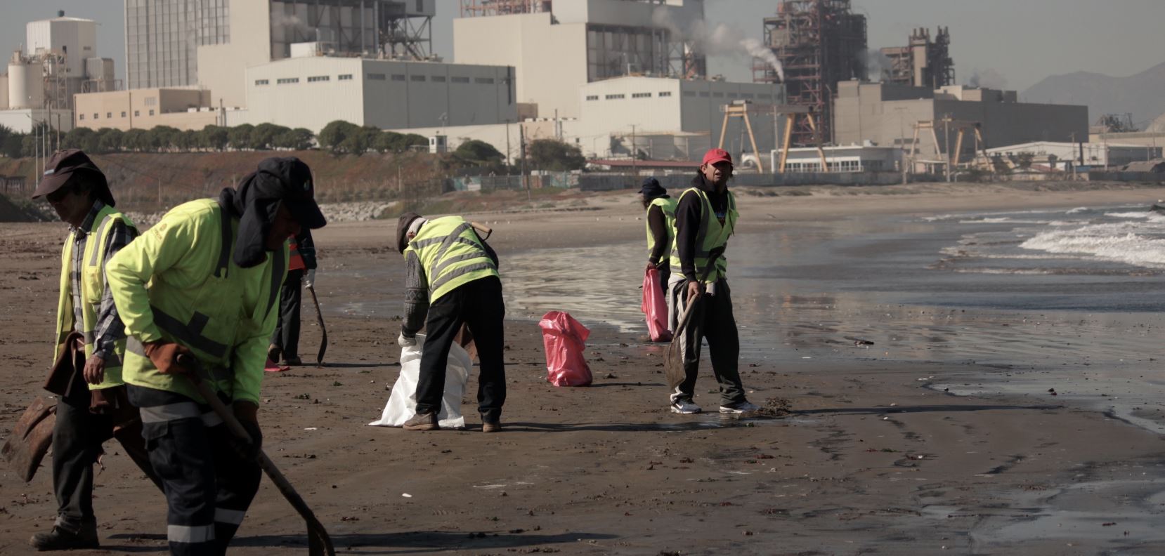 Pescadores recogen, con palas, el carbón de la playa. Foto: Michelle Carrere.
