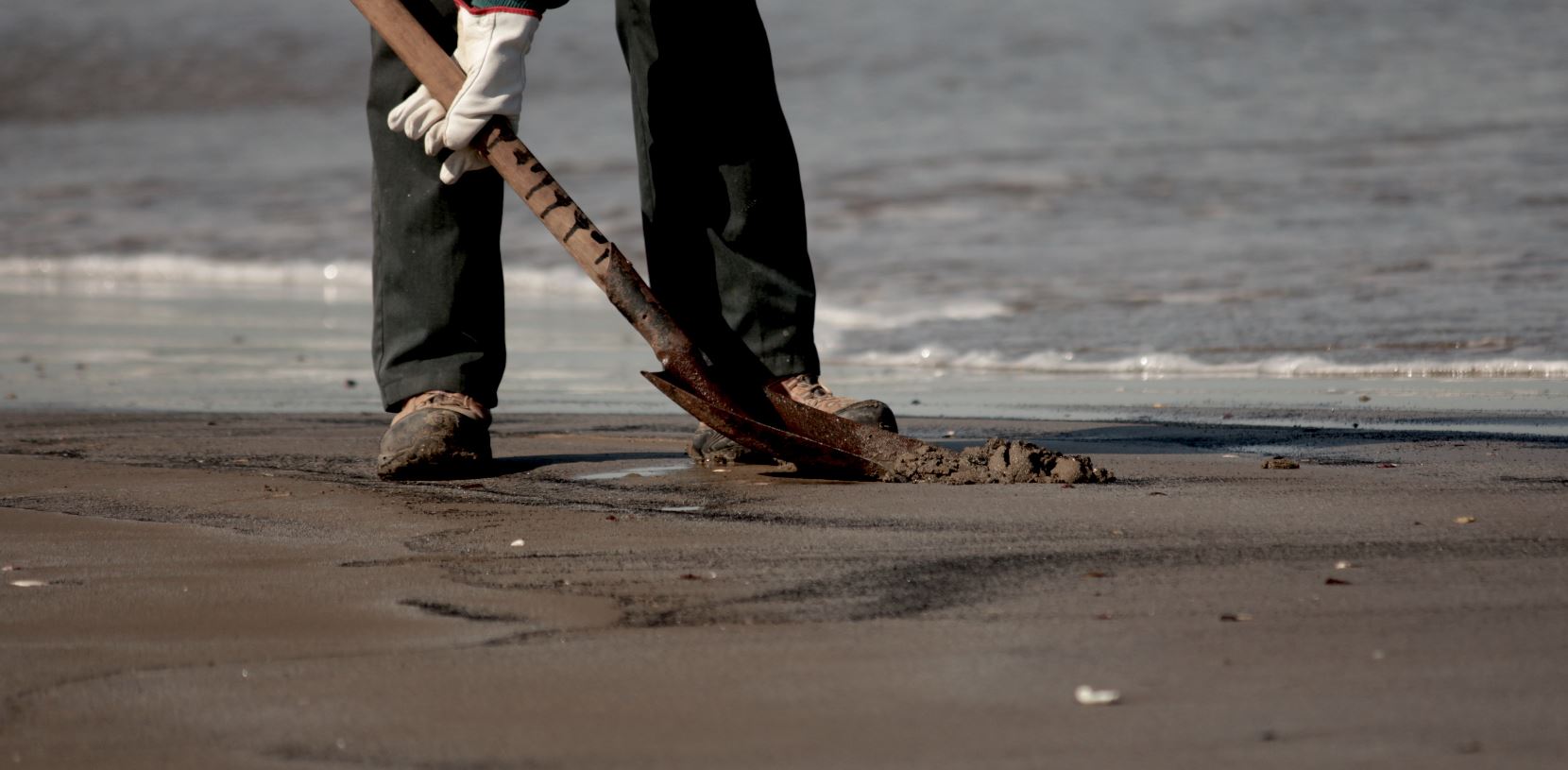 Pescadores recogen, con palas, el carbón de la playa. Foto: Michelle Carrere.
