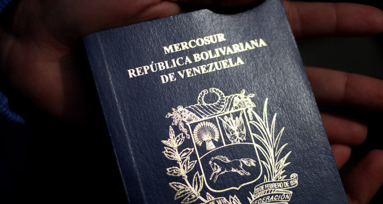 La imagen muestra las manos de una persona sosteniendo un pasaporte venezolano.