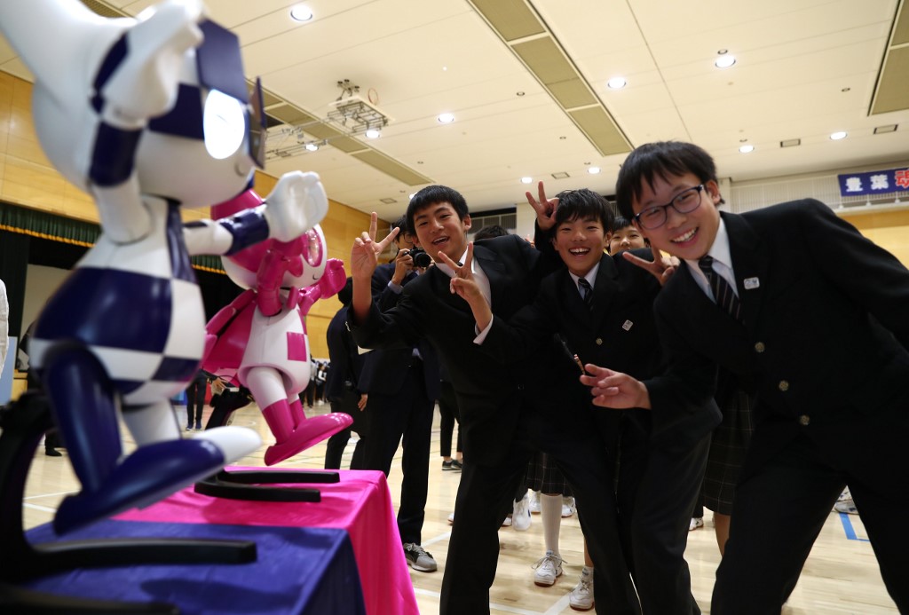 Schoolchildren interact with Tokyo 2020 Olympic and Paralympic Games' robot-type mascots Miraitowa and Someity during a ceremony at Hoyonomori elementary school in Tokyo on November 18, 2019. - Tokyo 2020 Summer Games' mascot robots visited an elementary school, drawing cheers and laughters from children as they gave them quizzes and responded to verbal instructions. (Photo by Behrouz MEHRI / AFP) / The erroneous mention[s] appearing in the metadata of this photo by Behrouz MEHRI has been modified in AFP systems in the following manner: [Miraitowa] instead of [Miraito]. Please immediately remove the erroneous mention[s] from all your online services and delete it (them) from your servers. If you have been authorized by AFP to distribute it (them) to third parties, please ensure that the same actions are carried out by them. Failure to promptly comply with these instructions will entail liability on your part for any continued or post notification usage. Therefore we thank you very much for all your attention and prompt action. We are sorry for the inconvenience this notification may cause and remain at your disposal for any further information you may require.