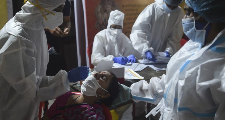 A health worker wearing protective gear collects a swab sample from a resident during a medical screening for the Covid-19 coronavirus at a police colony in Mumbai on September 16, 2020. – India’s total coronavirus cases passed five million on September 16, health ministry data showed, as the pandemic extends its grip on the vast country at an ever-faster rate. (Photo by Punit PARANJPE / AFP)