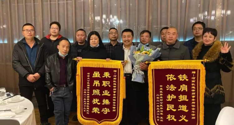 El abogado Ren Quanniu (centro, con un ramo de flores) posando con pancartas enviadas por ciudadanos de Zhengzhou “en agradecimiento a su trabajo”. | Leo Ramírez | Agence France-Presse