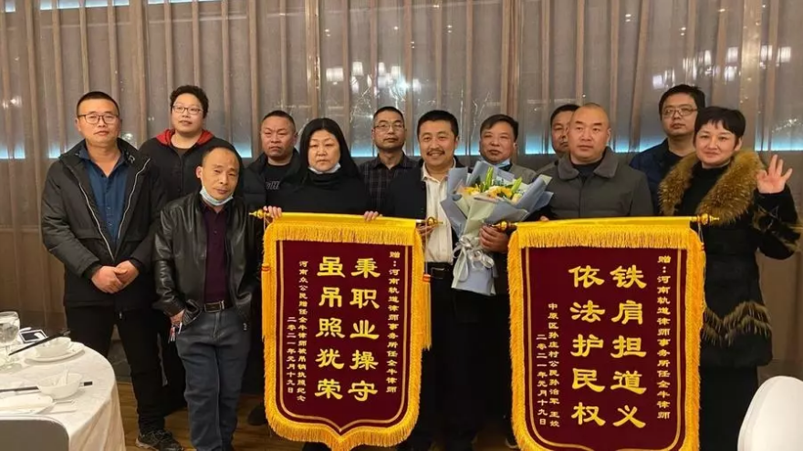 El abogado Ren Quanniu (centro, con un ramo de flores) posando con pancartas enviadas por ciudadanos de Zhengzhou “en agradecimiento a su trabajo”. | Leo Ramírez | Agence France-Presse