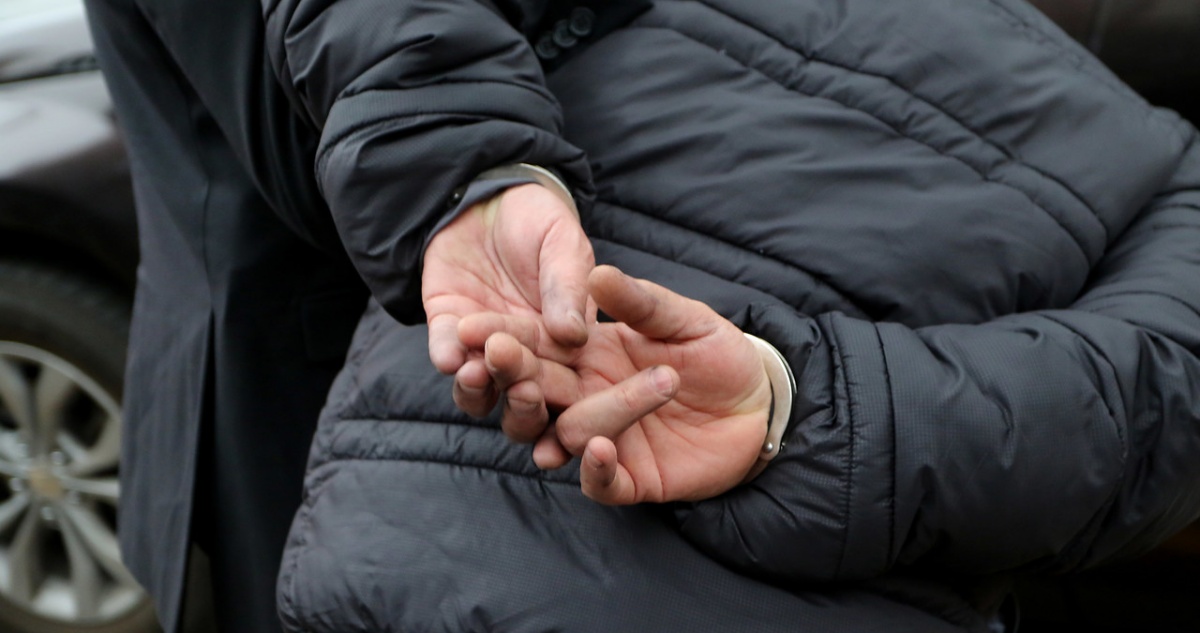 Hombre detenido esposado