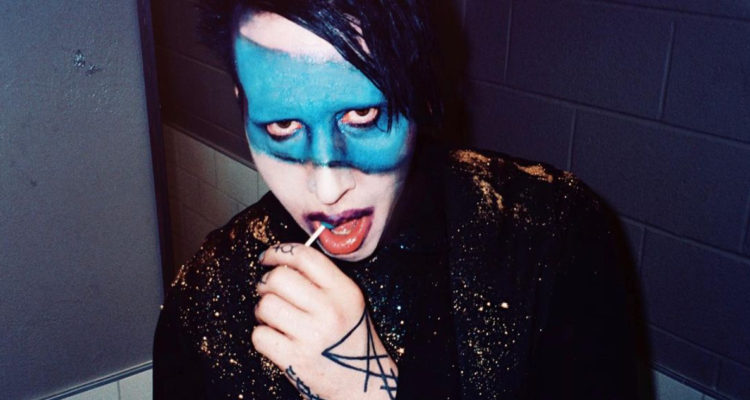 El cantante Marilyn Manson con un dulce en la boca mientras mira a la cámara.