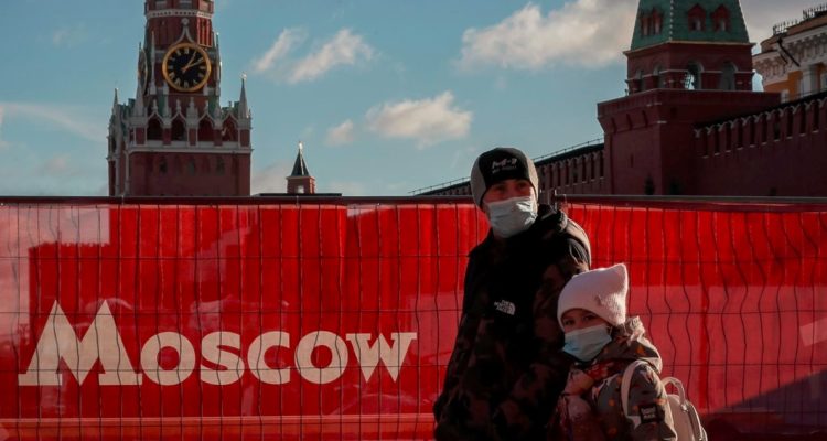 Hombre y niña caminan en Moscú con mascarillas.