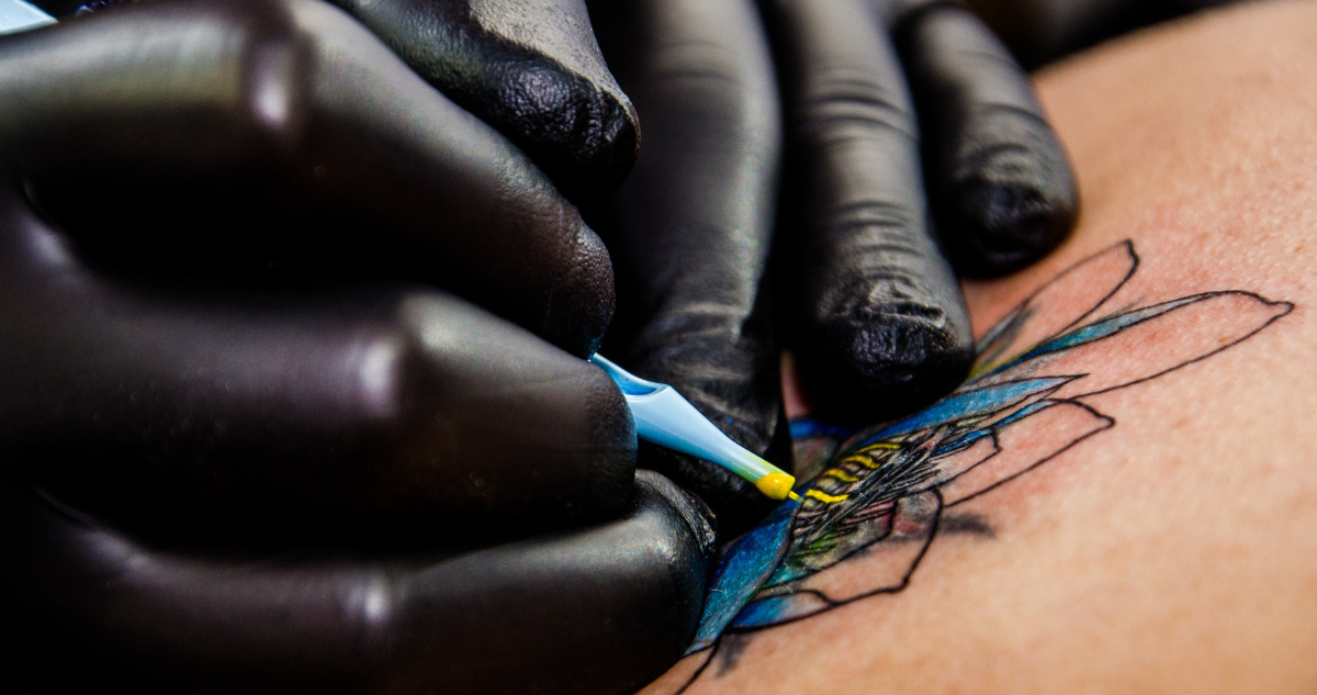 Las manos de un tatuador mientras realiza un tatuaje de mándala.