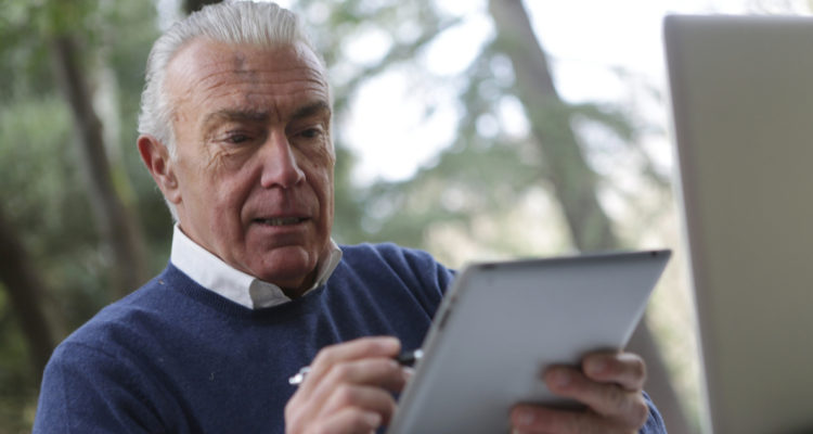 En la foto, un anciano sostiene una tablet.