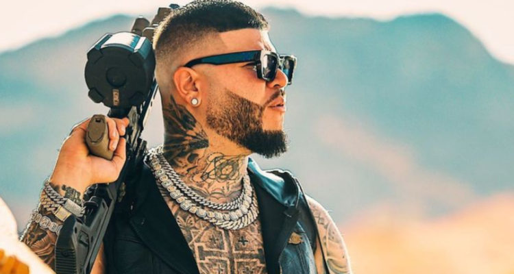 El cantante urbano Farruko aparece de lado posando con un arma falsa para un próximo video musical.