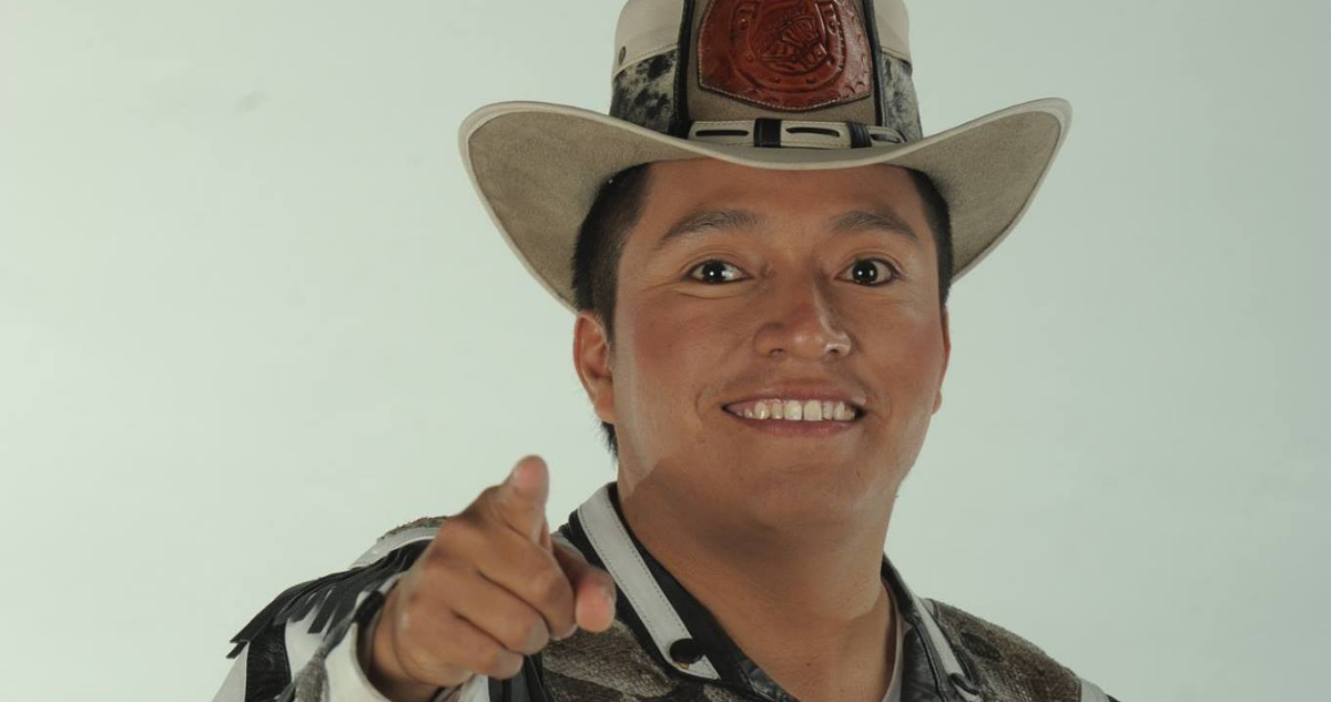 El cantante aparece con su clásico traje estilo ranchero sonriendo y apuntando a la cámara.