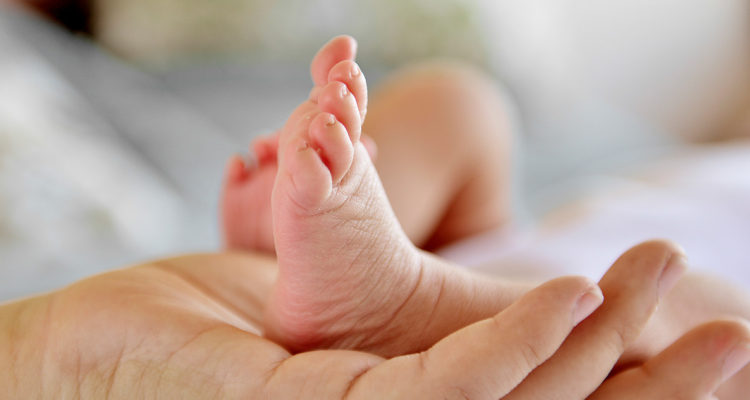 Pie de bebe y una mano adulta.