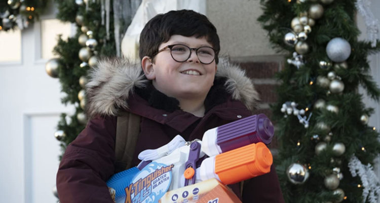 Archie Yates aparece sonriendo con ropa de nieve y una pistola de agua en sus brazos.