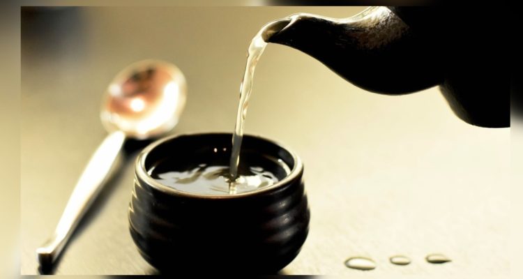 Tetera vierte agua a taza y deja gotas en la mesa.