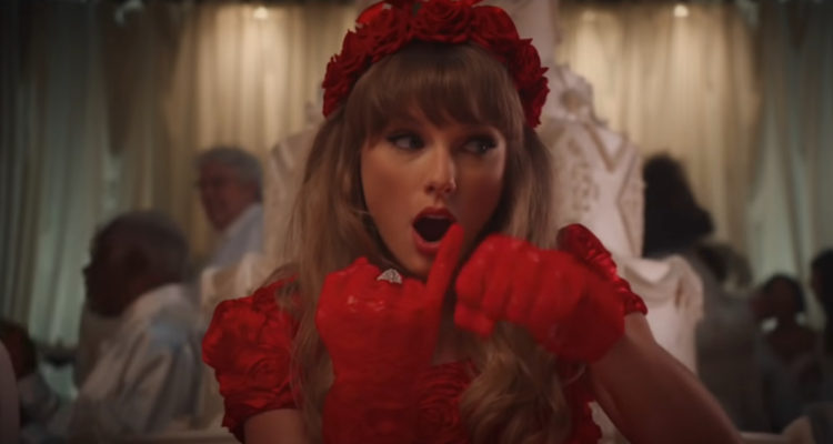 La cantante Taylor Swift sale vestida de rojo en medio de una boda donde todos visten de blanco y bromea con un grupo de niñas.