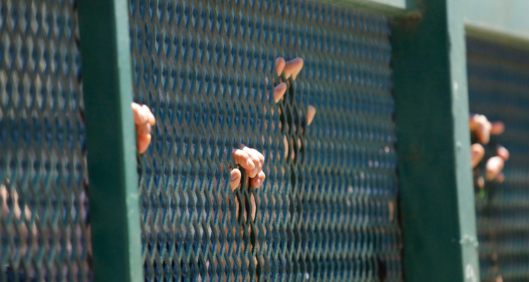 Manos en reja de cárcel