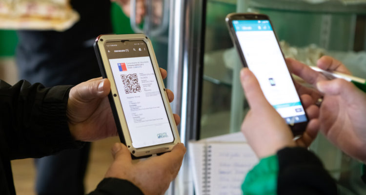 Una anfitriona de un restaurante solicita pase de movilidad a unos clientes para poder ingresar al local.