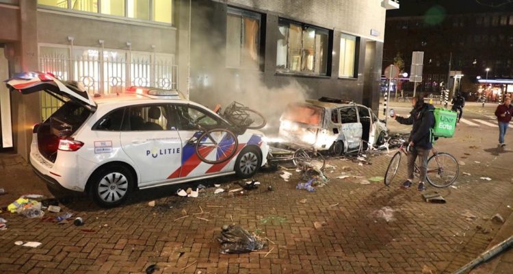 Un vehículo policial dañado y un automóvil civil quemado durante las protestas.