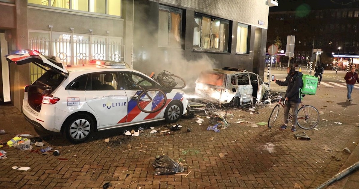 Un vehículo policial dañado y un automóvil civil quemado durante las protestas.