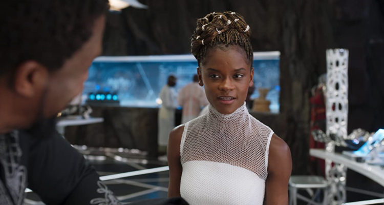La actriz Letitia Wright aparece personificada como Shuri, vestida de blanco mientras habla con Pantera Negra.