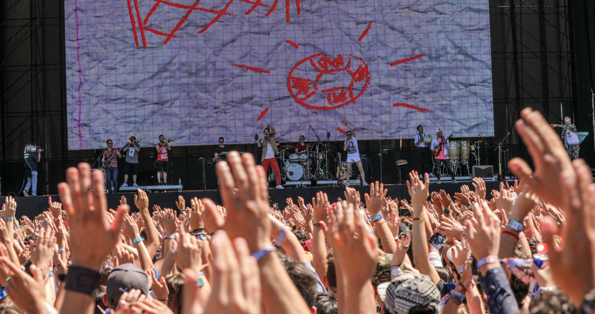 Una multitud alza sus manos en medio de una presentación del festival Lollapalooza.