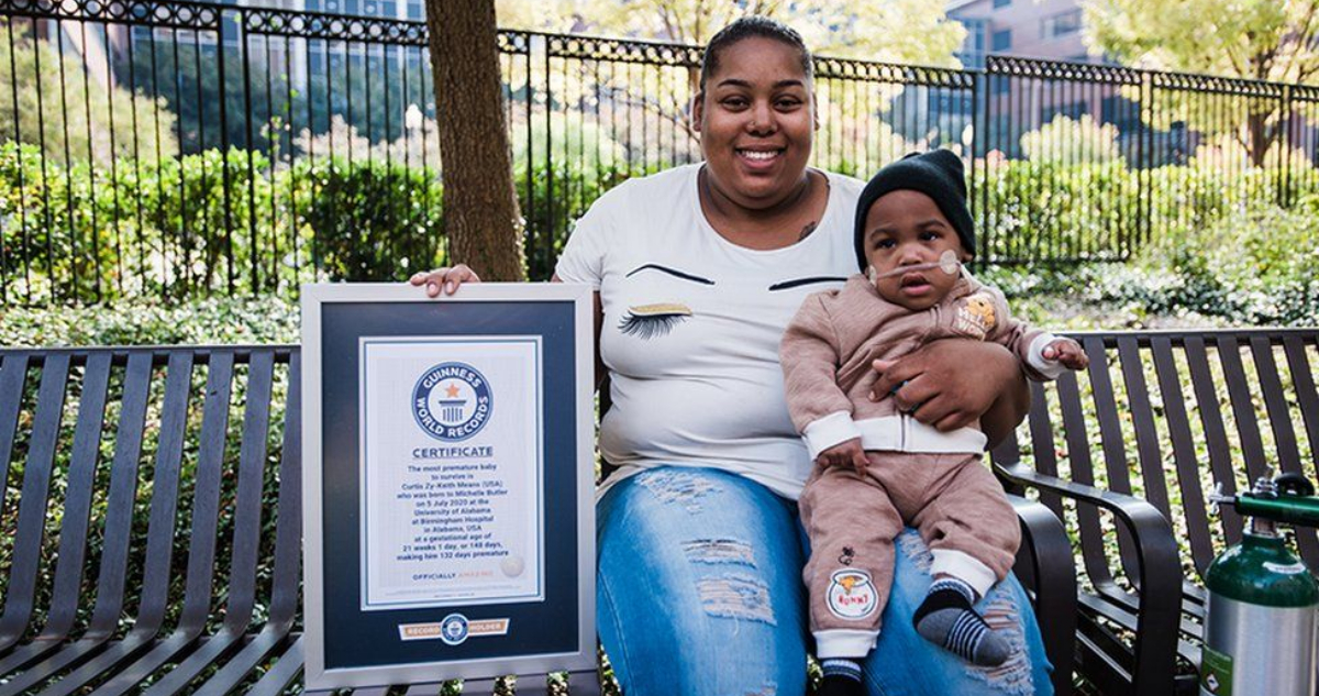 En un parque, la madre del pequeño sostiene al bebe ya con más de un año de edad. También muestra el certificado de su récord mundial.