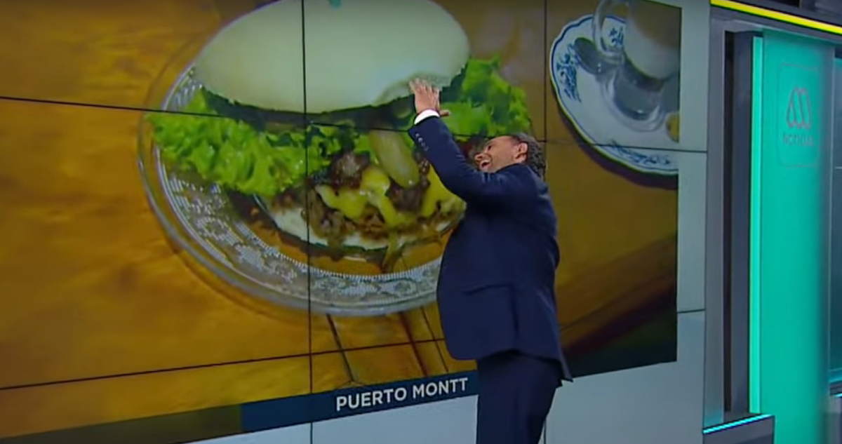 El periodista Rodrigo Sepúlveda reacciona aparentando comer el sándwich desde la pantalla del estudio.