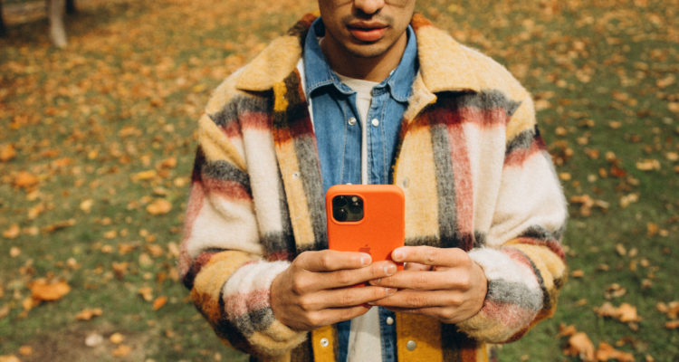 Un hombre sostiene mira su celular en un parque.
