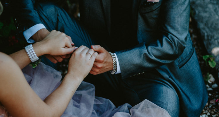 En la foto, un hombre y una mujer aparecen sostenidas de la mano. LLevan un aniñño de bodas y están vestidos para la ocasión.