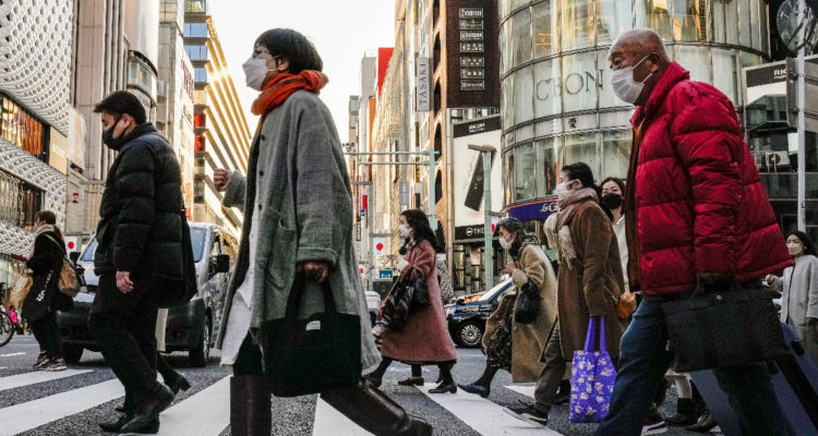 Un grupo de personas cruzando una calle. Todas usan mascarillas para protegerse del covid-19.
