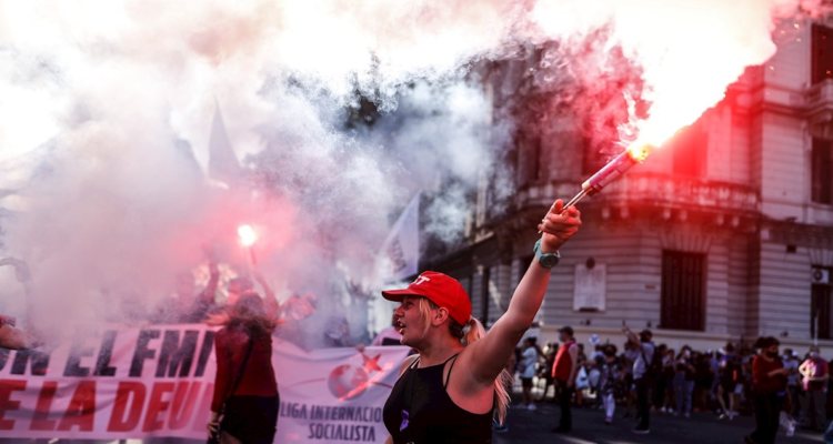 Mujer con una bengala en su mano, marcha en rechazo al acuerdo del gobierno argentino y el FMI