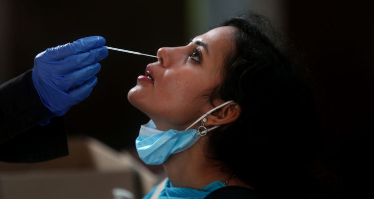 Una funcionaria de salud recibe el test PCR en medio de la nueva hola por COVID-19 debido a la variante Ómicron.