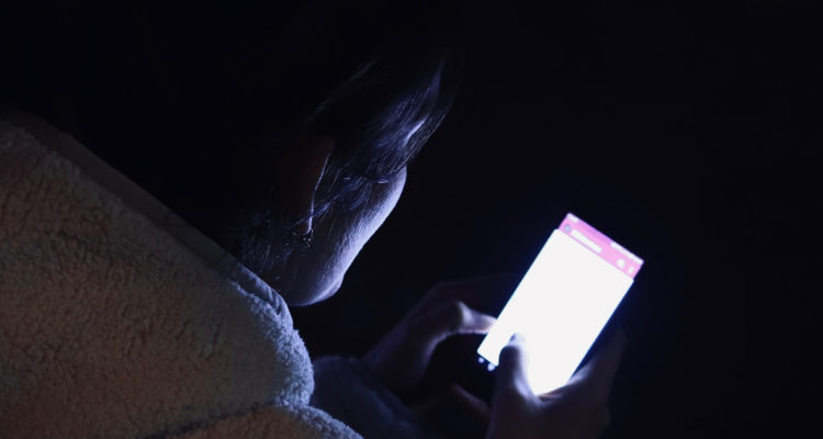 Una mujer utiliza un celular en la noche, un ejemplo de Vamping.
