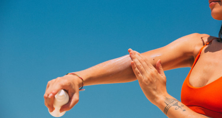 Una mujer se aplica protector solar en uno de sus brazos.