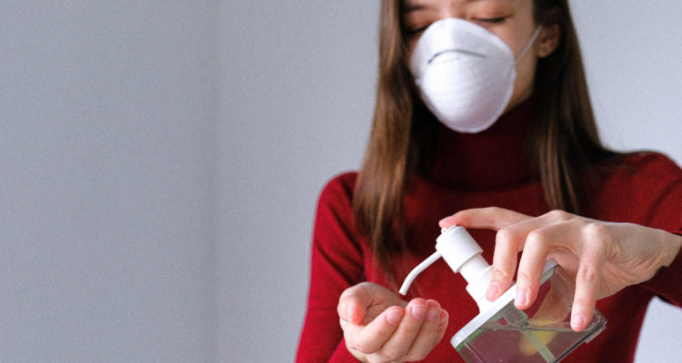 Una mujer con mascarilla utiliza alcohol gel para limpiar sus manos en medio de la ola de la variante Ómicron.