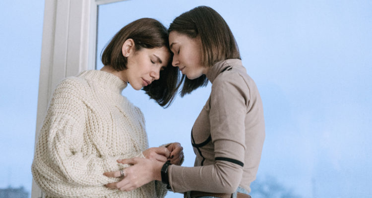 Dos mujeres tienen sus rostros juntos, en señal de que una le muestra apoyo emocional a la otra que parece tener depresión.