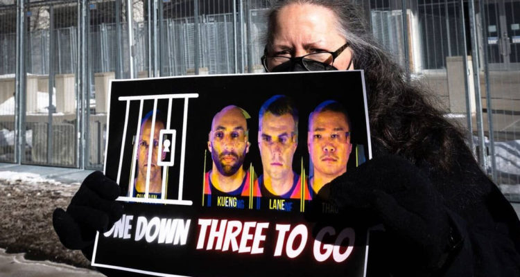 Una manifestante sujetando un cartel con las caras de los cuatro policías involucrados.