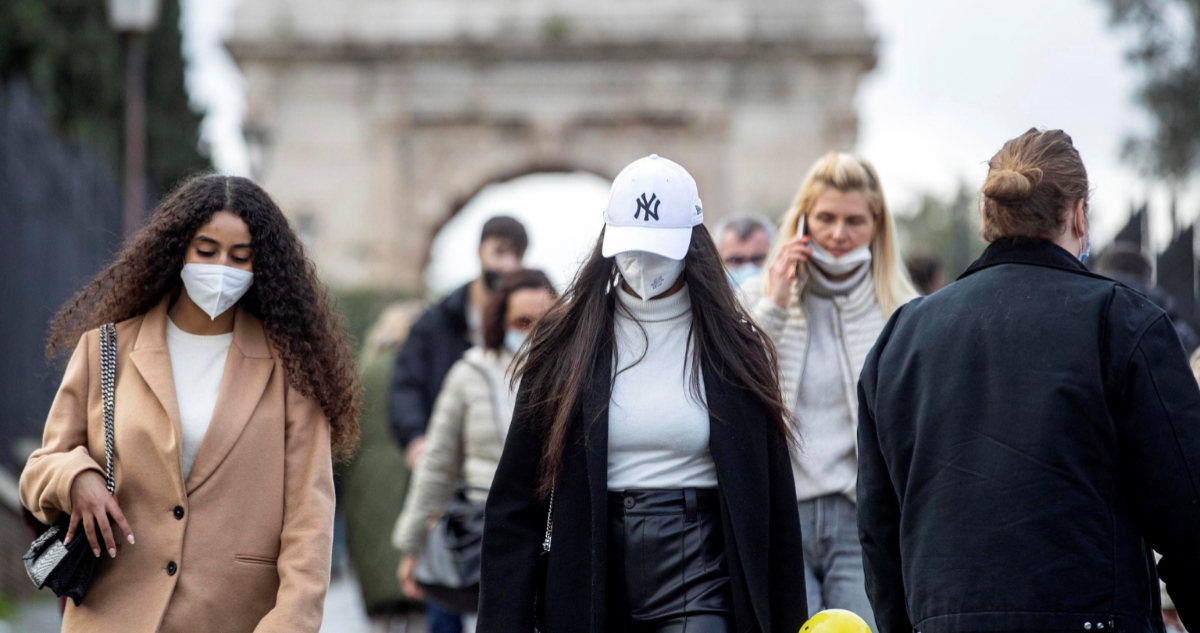 Dos mujeres caminando mientras usan mascarillas en la calle en medio del aumento de casos por ómicron.
